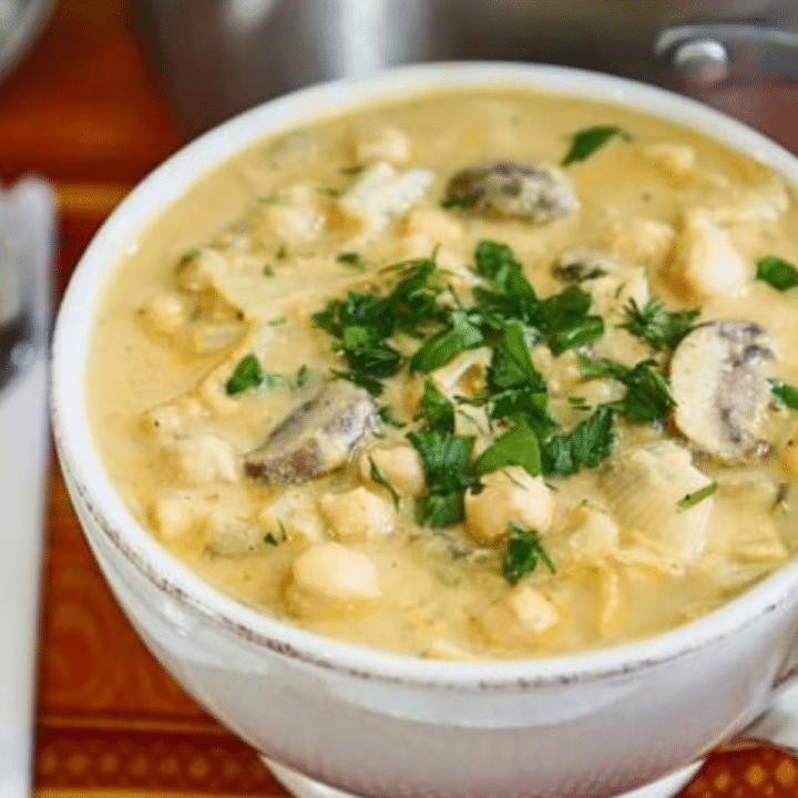 Chickpea-mushroom soup with tahini in a white mug, topped with fresh parsley