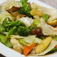 Chinese vegetable stir fry (Buddha's Delight) with broccoli, cabbage, baby corn and snap peas on a white plate