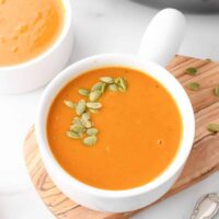 Coconut curry pumpkin soup in a white bowl garnished with pumpkin seeds