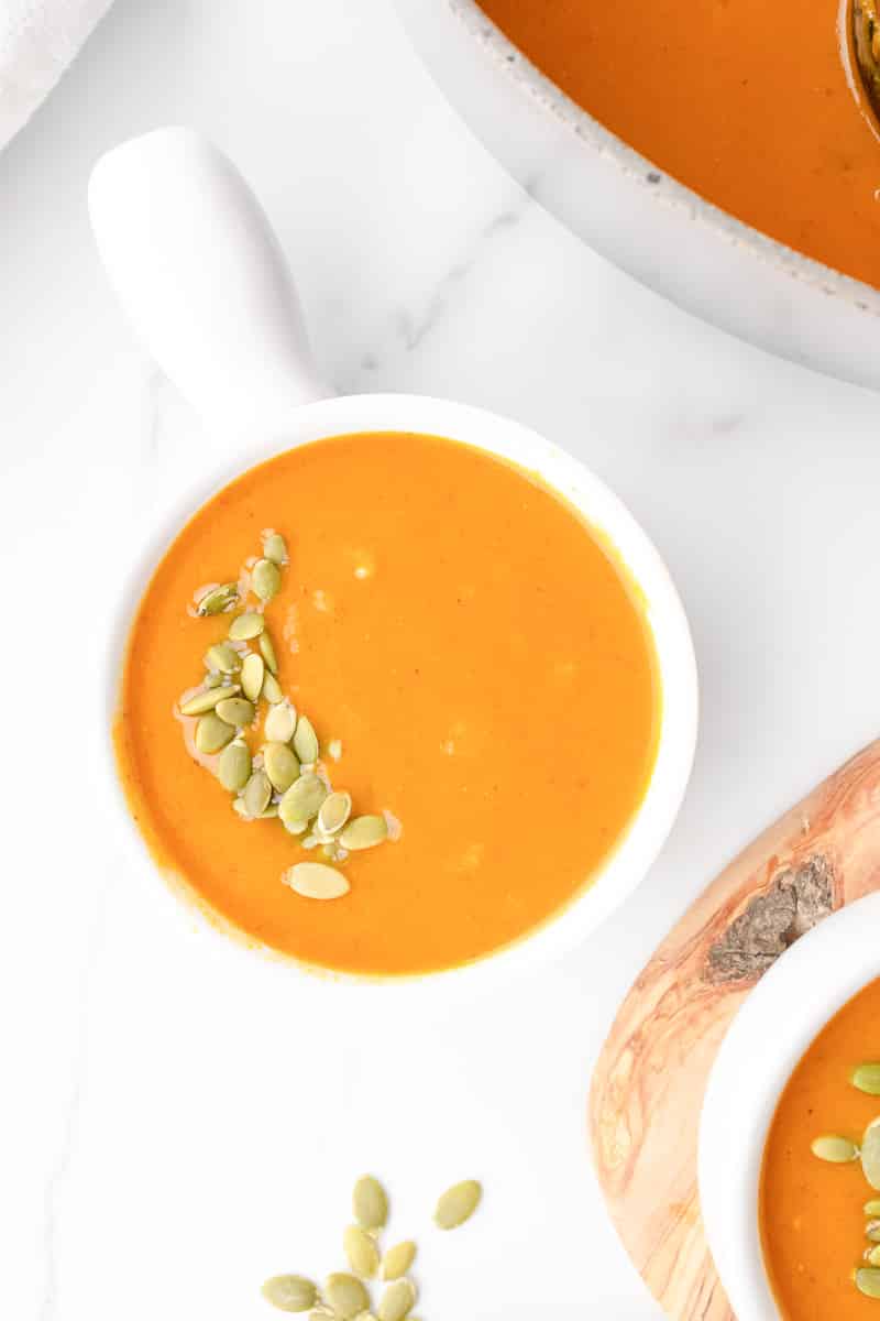 Overhead view of creamy coconut curry pumpkin soup with toasted pumpkin seeds