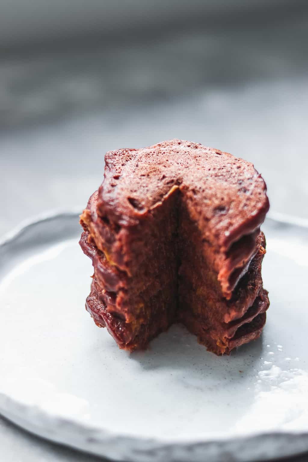 Stack of chocolate pumpkin pancakes with a wedge cut out showing the fluffy inside