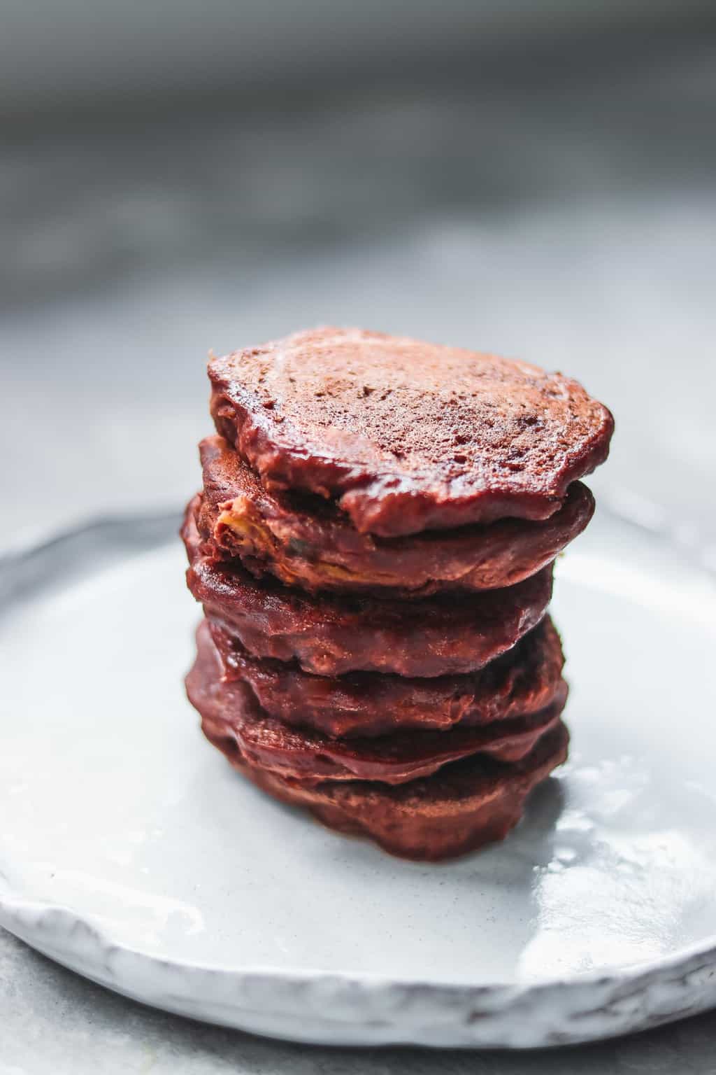 Stack of gluten-free chocolate pumpkin pancakes on a rustic white plate