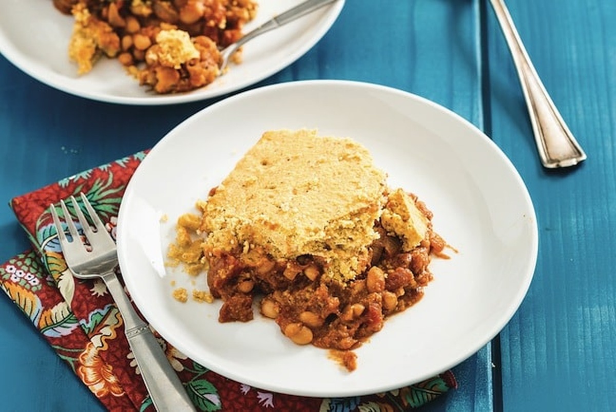 Close-up landscape view of maple baked beans and cornbread casserole served on a white plate