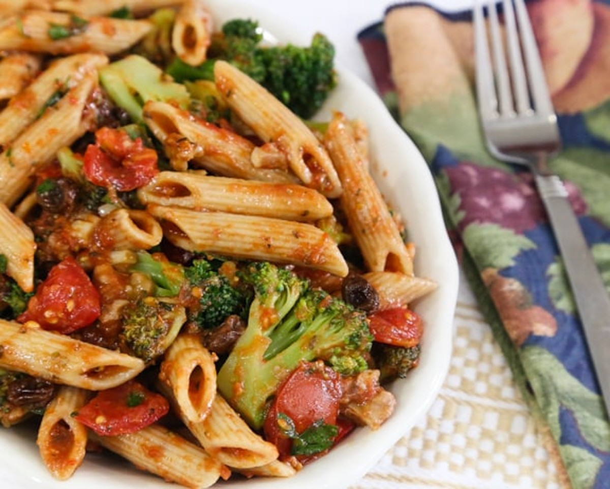 Close-up of penne with broccoli, tomatoes, walnuts, and raisins