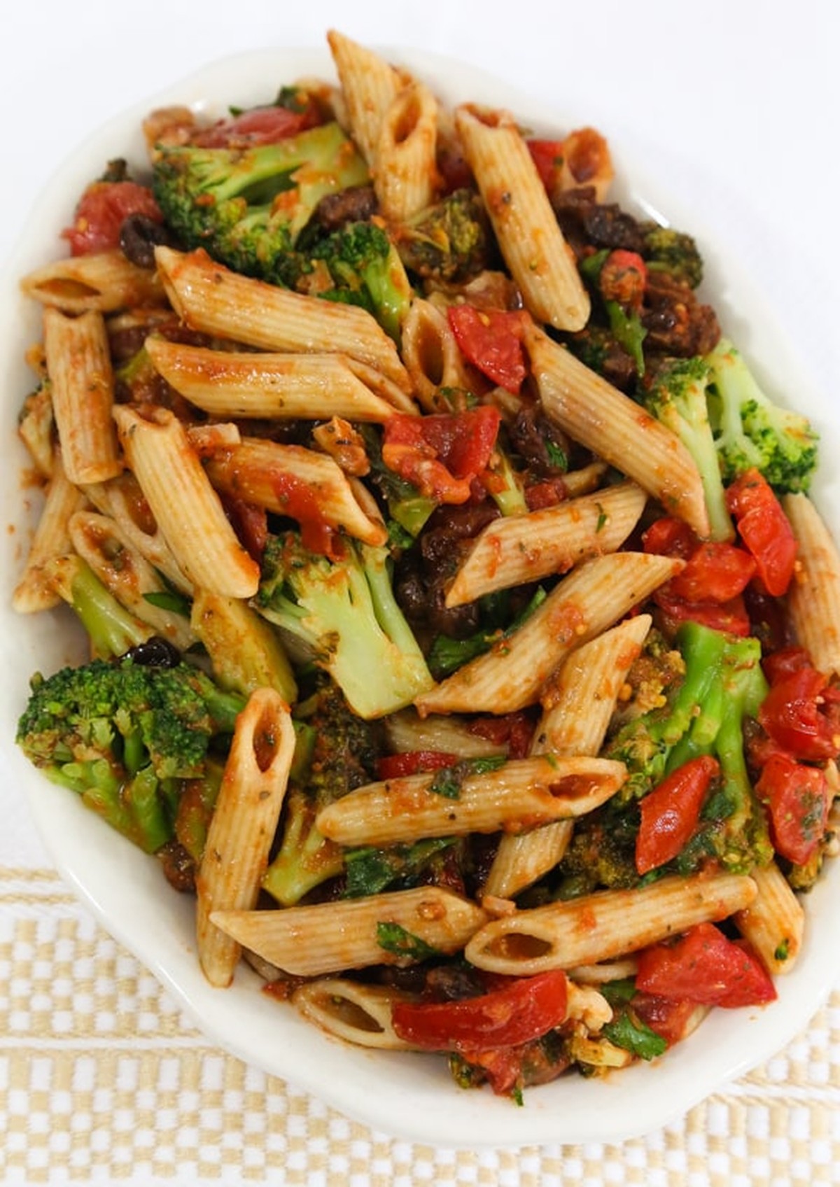 Bowl of penne with broccoli, tomatoes, walnuts, and raisins