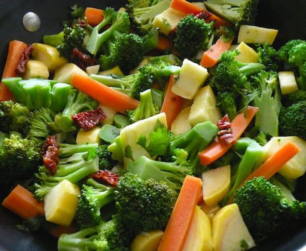 Close-up of sautéed broccoli, carrots, yellow squash, and sun-dried tomatoes in a skillet