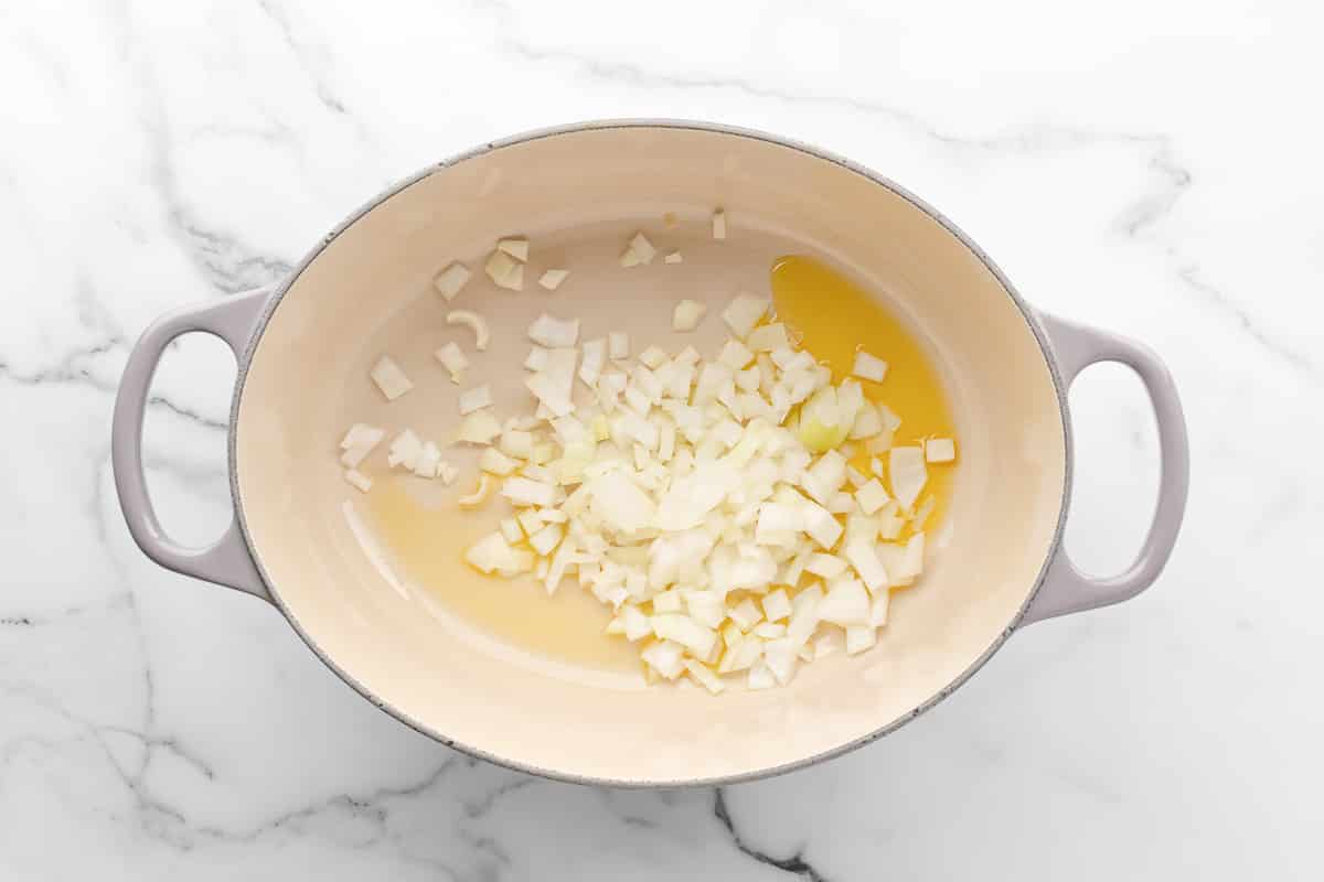 Diced onion sauteing in olive oil in a white Dutch oven