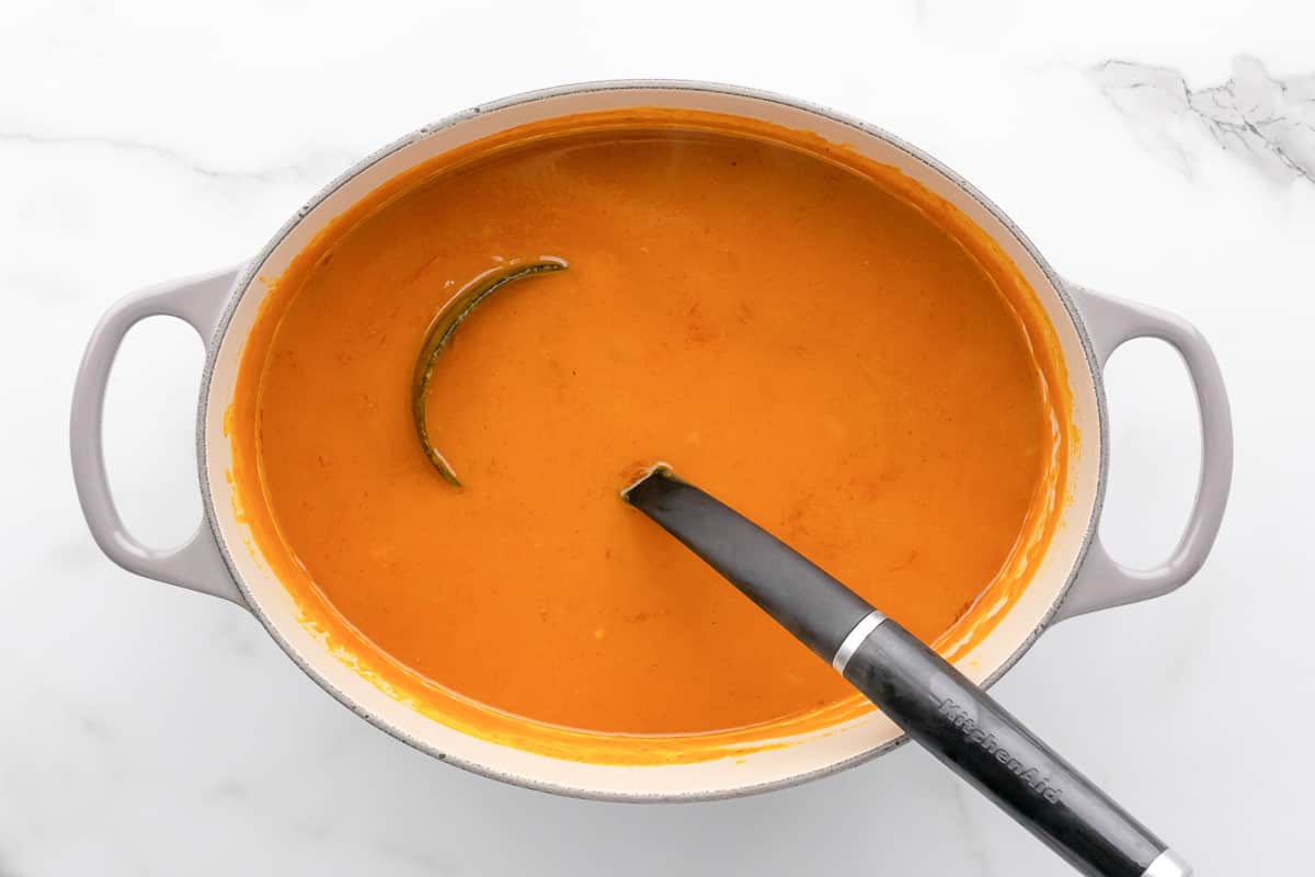 Smooth simmered curry pumpkin soup in a pot with a ladle