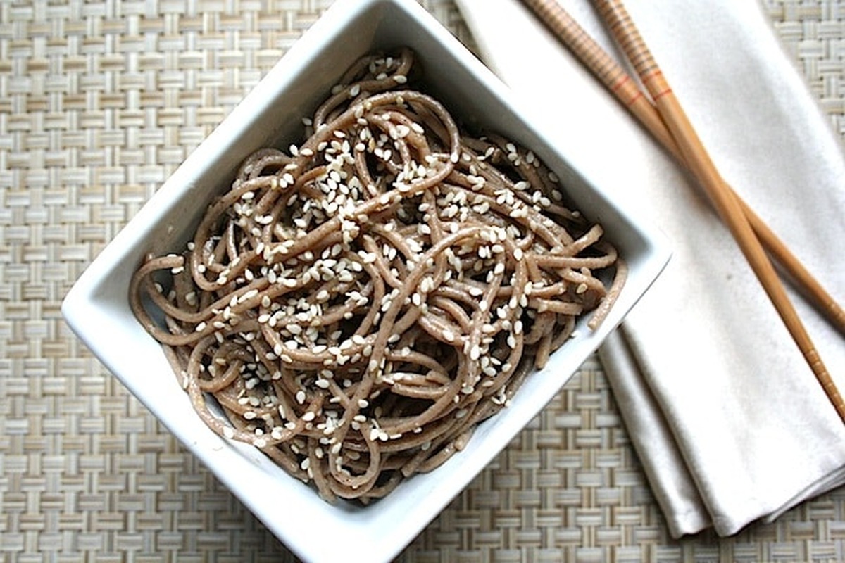 Overhead view of vegan sesame soba noodles in a white bowl with chopsticks