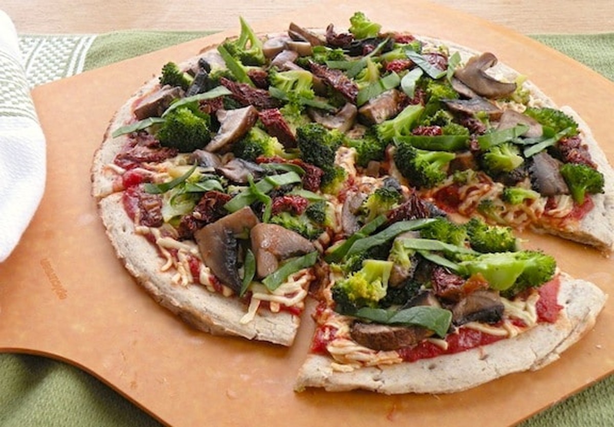 Close-up of vegan broccoli, mushroom, and sun-dried tomato pizza