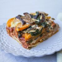 Slice of vegan butternut squash and Swiss chard lasagna on a white plate