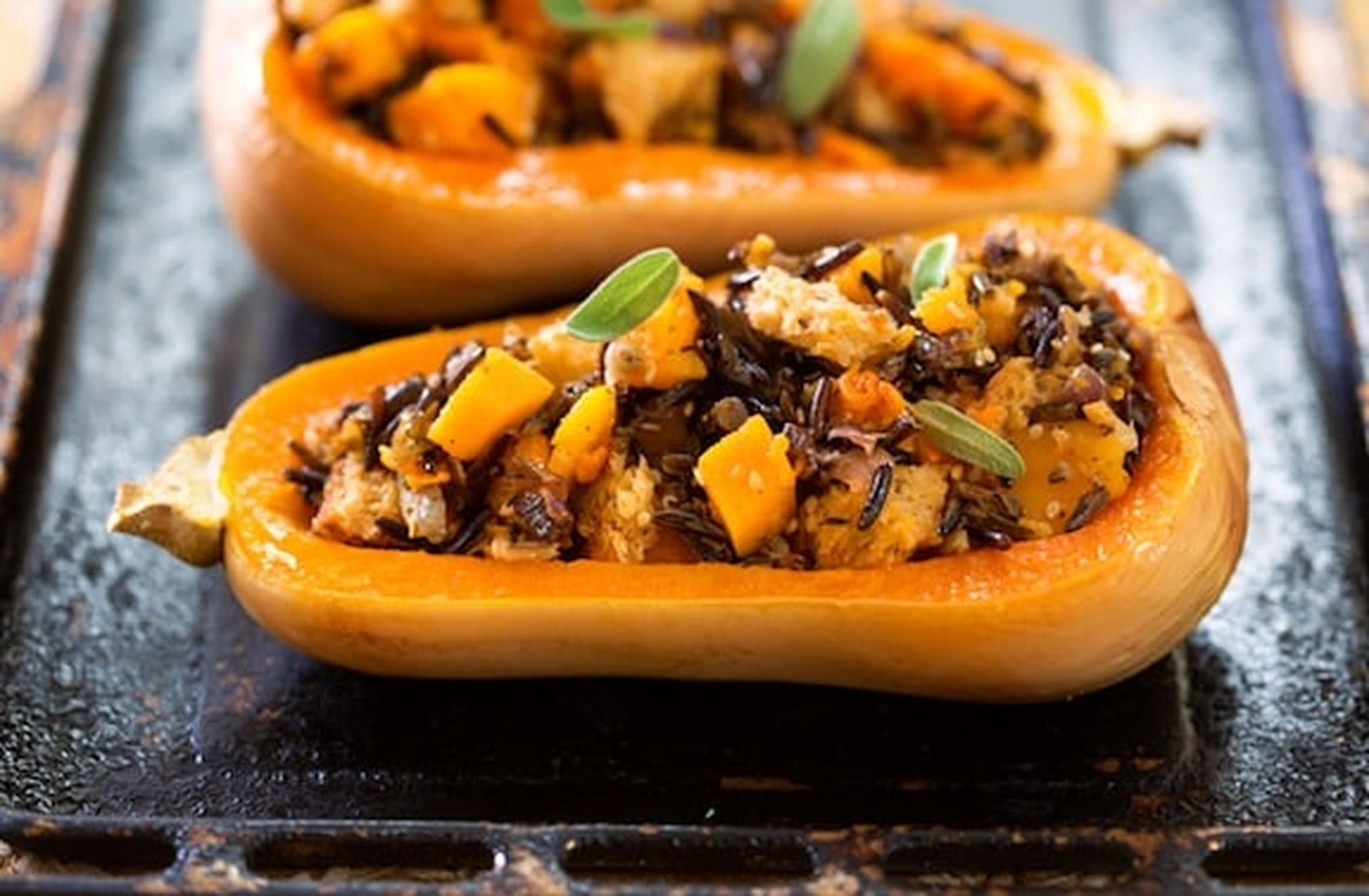 Close-up of two roasted vegan butternut squash boats filled with wild rice and onion stuffing
