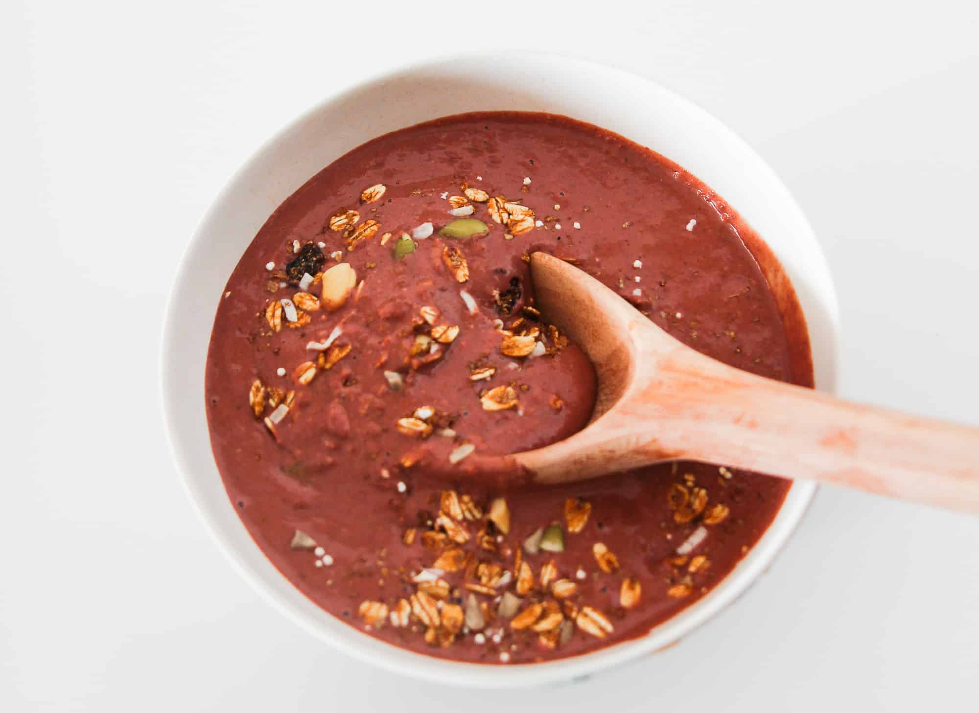 Blended chocolate raspberry smoothie in a bowl before adding granola and fresh fruit toppings