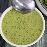 Overhead view of vegan green goddess dressing in a white bowl with a spoon resting on top