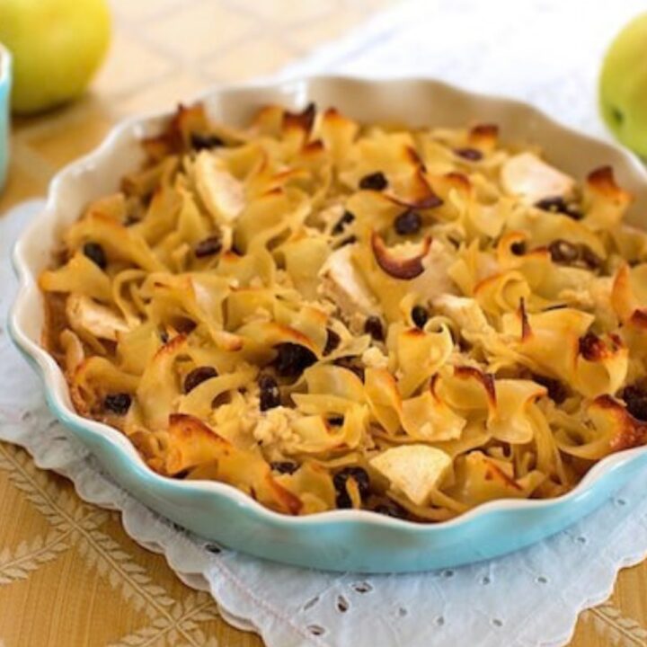 Vegan noodle kugel with raisins and apples in a scalloped baking dish