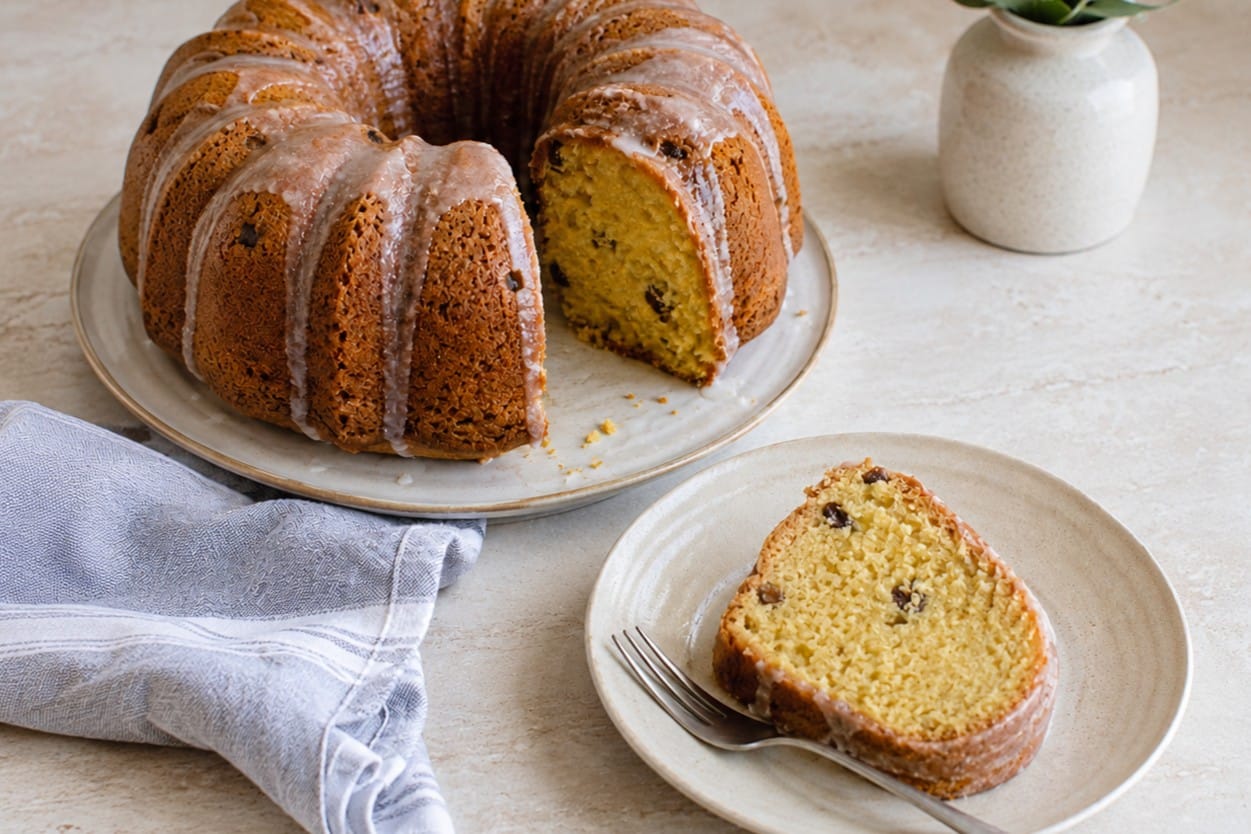 Vegan orange bundt cake with a slice cut, showing raisins throughout