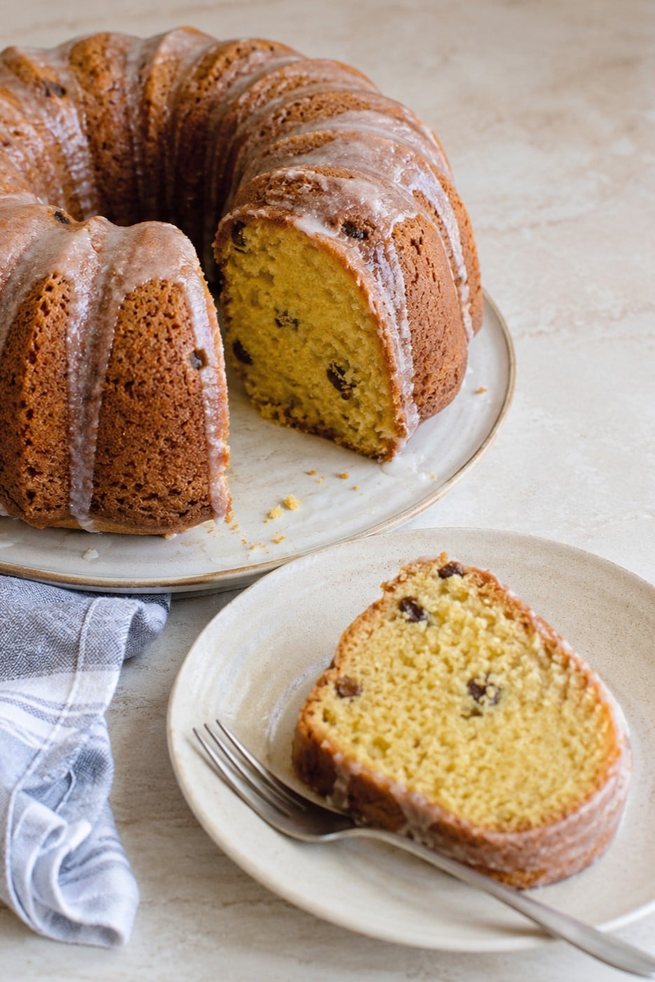 Slice of vegan orange bundt cake with raisins and orange cream glaze