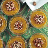 Vegan pumpkin mousse in glass dessert cups topped with chopped pecans