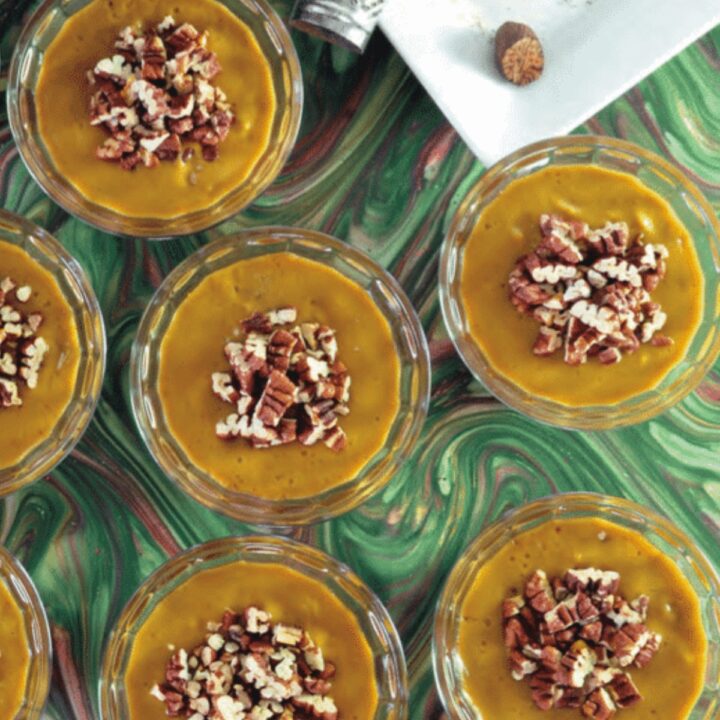 Vegan pumpkin mousse in glass dessert cups topped with chopped pecans