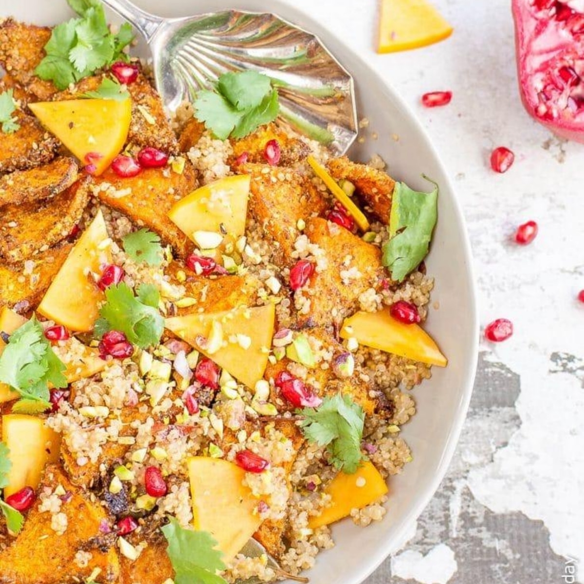 Close-up of quinoa pilaf with roasted squash, persimmon slices, pistachios and pomegranate