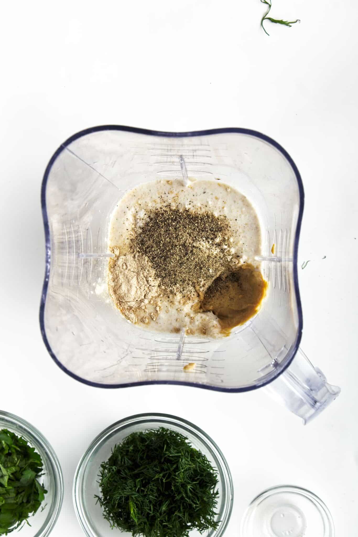 Vegan ranch dressing ingredients being blended with garlic powder and black pepper visible