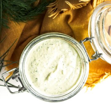 Vegan ranch dressing with fresh herbs in a glass jar, top-down view