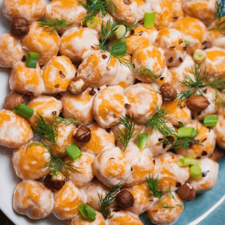 Vegan sweet potato gnocchi with dill, green onion and hazelnuts on a blue plate