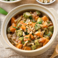 West African peanut and okra stew with sweet potatoes and chopped peanuts in a cream ceramic pot