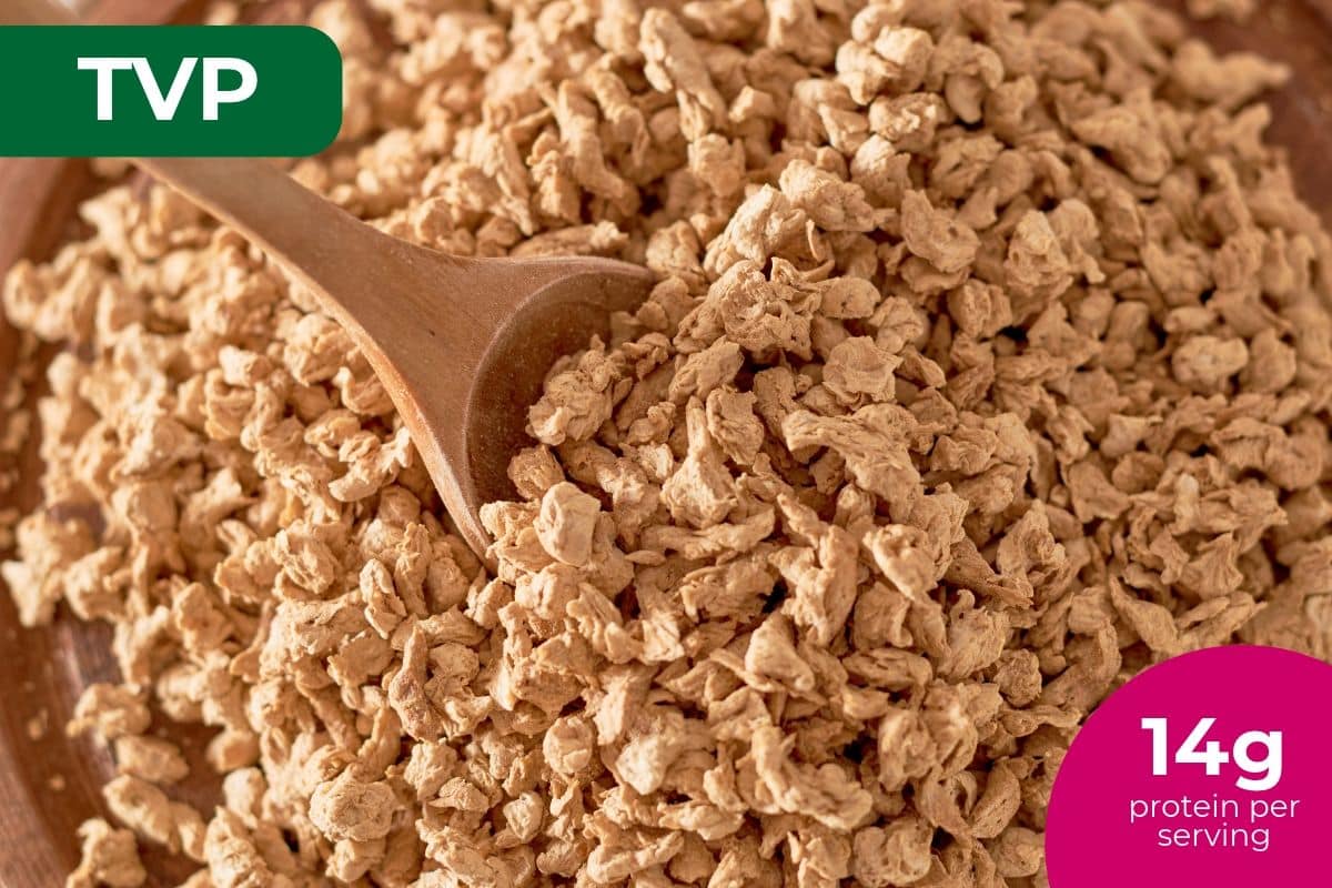Dry textured vegetable protein crumbles with a wooden spoon, labeled 14 g protein per serving