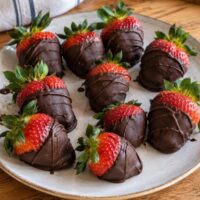 Vegan chocolate covered strawberries drizzled with dark chocolate on a white plate