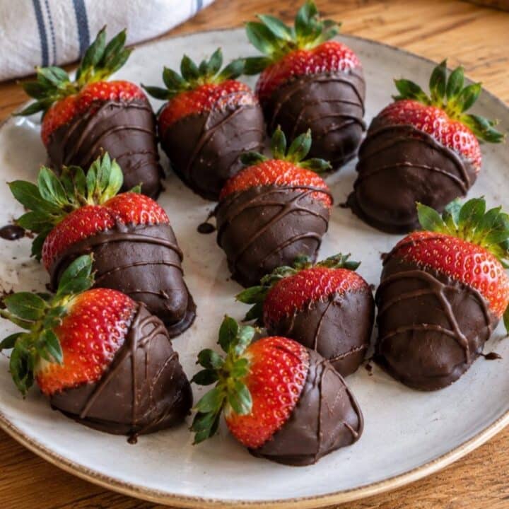 Vegan chocolate covered strawberries drizzled with dark chocolate on a white plate